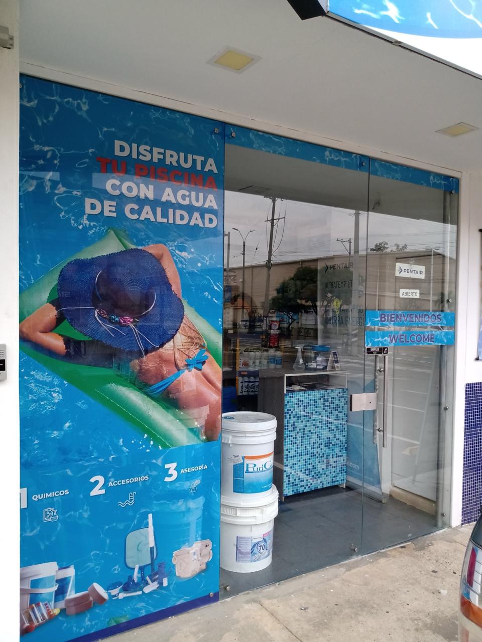Entrada de ArquiPiscinas con aviso de bienvenida y productos químicos en vitrina